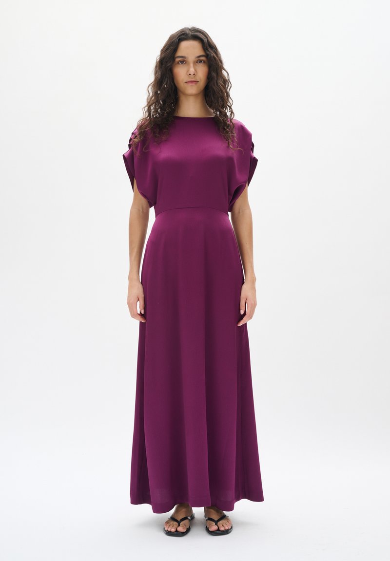 Robe maxi en violet profond, avec un décolleté carré, des manches courtes en forme de chauve-souris, et un tissu lisse et fluide qui tombe jusqu'au sol.