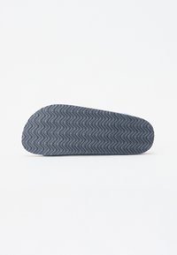 Grå gummisul med vågig textur och rundade kanter, designad för grepp och flexibilitet. Enkelt och minimalistiskt design.