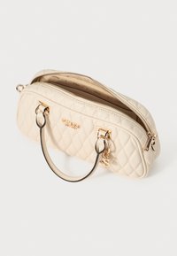 White quilted handbag with a dual zip closure, gold-tone hardware, and short, rounded black handles. The interior features a brand-patterned lining.