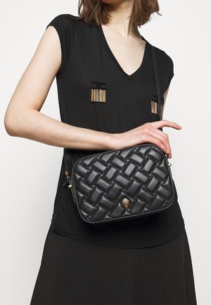 Svart quiltad läder crossbody-väska med guldhardware, som har ett vävt mönster och ett dekorativt lås. Kompakt rektangulär form.