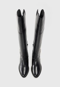 Botas negras hasta la rodilla hechas de cuero suave con punta afilada y un diseño recortado en la parte superior. Cuentan con cierre lateral y acentos de hardware dorado.