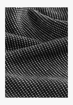 Textúrált szövet fekete háttérrel és kis fehér négyzetekből álló rácsos mintával, amely ritmikus dizájnt és lágy megjelenést kölcsönöz.