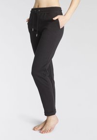 Schwarze Jogginghose mit tailliertem Design, elastischem Bund und Kordelzug. Verfügt über Seitentaschen und einen Bündchenabschluss.