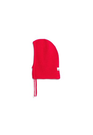 Red knitted beanie with a pointed top, featuring side ties and a small label on the side. Textured fabric with ribbed detailing.