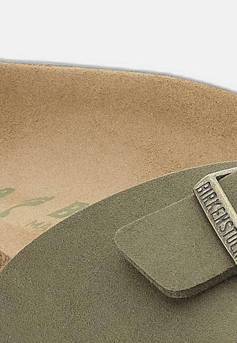 Groene leren sandaal met een brede band en metalen merkaccent. Kurk voetbed in een lichtbeige kleur. Minimalistisch ontwerp en een gladde textuur.