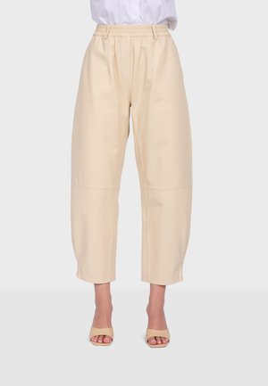 Beige high-waist, wide-leg cropped pants with elastic waistband worn with beige open-toe heels and a white tucked-in top.