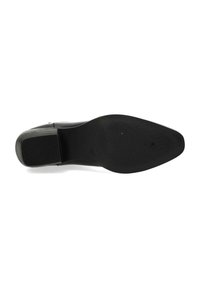 Svart lädersula på klädskor med spetsig form, texturerat gummigrepp och minimalistisk design. Har en jämn yta och tydligt mönster.