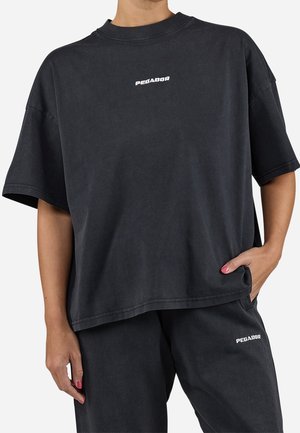 Černé oversize tričko s krátkým rukávem vyrobené z bavlny, s bílým logem "PEGADOR" přes hruď a uvolněným střihem.