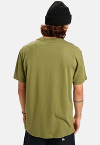 Olivově zelené bavlněné tričko s krátkým rukávem a kulatým výstřihem; obsahuje jemný šev na lemu a logo na zadní straně.