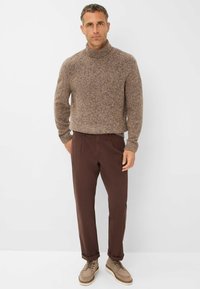 Braun gesprenkelter Wollrollkragenpullover kombiniert mit braunen Baumwollhosen und hellbraunen Schnürschuhen, vor einem weißen Hintergrund präsentiert.