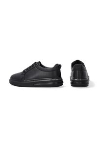 Schwarze Ledersneaker mit glatter Textur, abgerundeter Spitze, schnürbarem Design und dicker, gepolsterter schwarzer Sohle. Minimale Akzente.