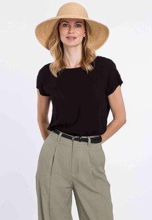 Top corto nero a maniche corte abbinato a pantaloni verde chiaro a vita alta e un cappello di paglia a tesa larga. Presenta una texture liscia e una vestibilità comoda.