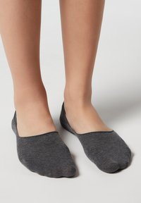 Chaussettes de cheville grises en tricot à plat avec un design bas, texture lisse et bout arrondi. Les bords sont renforcés, adaptées pour un port décontracté.