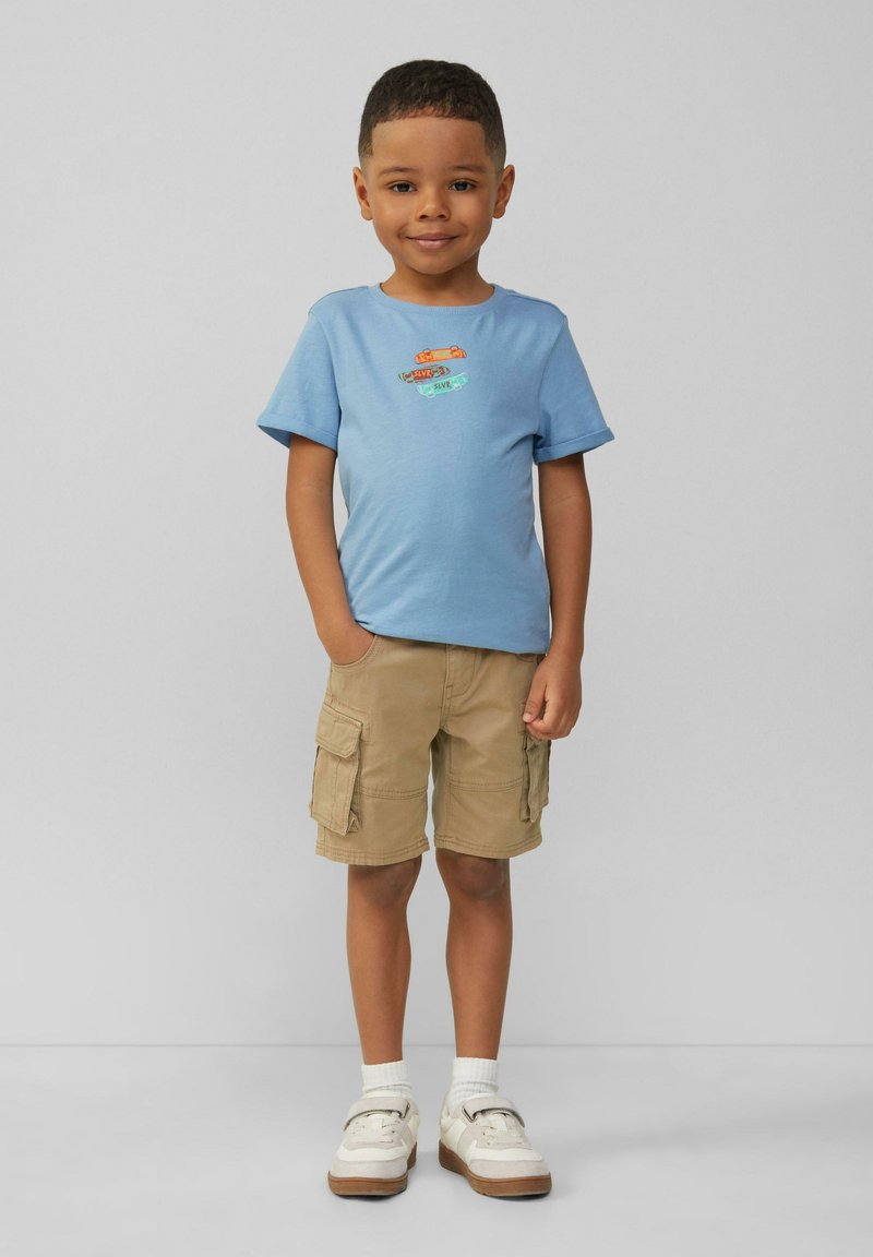 Lichtblauw overhemd met korte mouwen met kleurrijke autografieken, gecombineerd met kaki cargoshorts. Witte sokken en beige sneakers maken de outfit compleet.