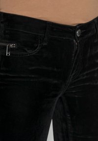 Svarta sammetbyxor med smal passform, med en liten dragkedjeficka och en standard knäppning. Mjuk textur och jämn glans.