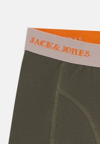 Olive green boxer shorts with a pink waistband featuring "JACK & JONES" in orange text, showcasing a close-up of the fabric and stitching.