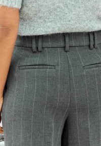 Grau gestreifte Hose mit glatter Textur, ausgestattet mit Gürtelschlaufen, zwei Gesäßtaschen und einem taillierten Schnitt.