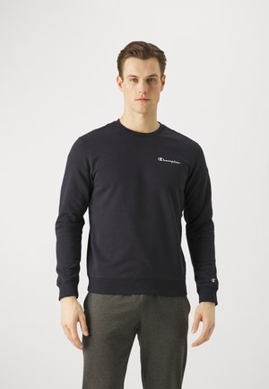 Felpa blu scuro in misto cotone, con scollatura rotonda e polsini a costine. Piccolo logo "Champion" bianco sul petto.