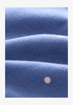 Modrá tkanina s jemnou textúrou, zobrazujúca záhyby a malý svetlý bodkovaný vzor. Povrch pôsobí hladko a mierne chlpatý.