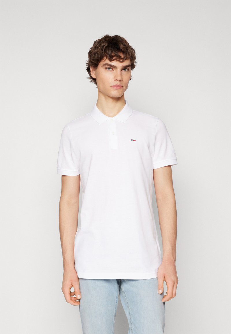 Camiseta polo de algodón blanco con una abertura de dos botones, mangas cortas y un pequeño logo bordado en el pecho. Corte casual.