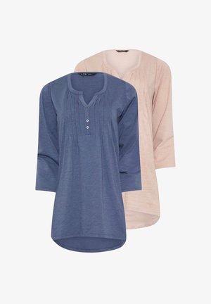 Due camicie: una di colore blu scuro con scollo a V, pattina con bottoni e pieghe; l'altra di un beige chiaro con un design simile. Tessuto morbido e informale.