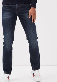 Donkerblauwe denim jeans met een rechte pasvorm, voorzien van contrasterende oranje stiksels, voorzakken en lichte vervaging op de benen.
