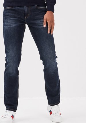 Dunkelblaue Denim-Jeans mit geradem Schnitt, mit kontrastierenden orangen Nähten, Fronttaschen und leichter Ausbleichung an den Beinen.