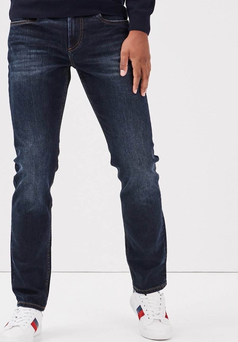 Donkerblauwe denim jeans met een rechte pasvorm, voorzien van contrasterende oranje stiksels, voorzakken en lichte vervaging op de benen.