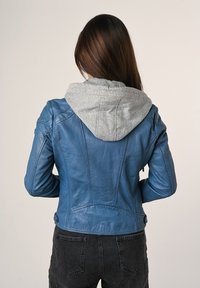 Giubbotto di pelle blu con cappuccio grigio, dal design aderente, texture liscia e dettagli delle cuciture sulla schiena.