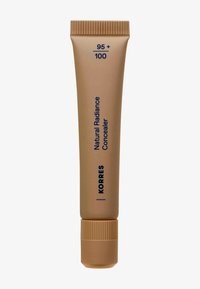Concealer éclat naturel Korres en teinte 95+100, tube beige avec un capuchon à vis, texte vertical bleu foncé sur fond marron clair.
