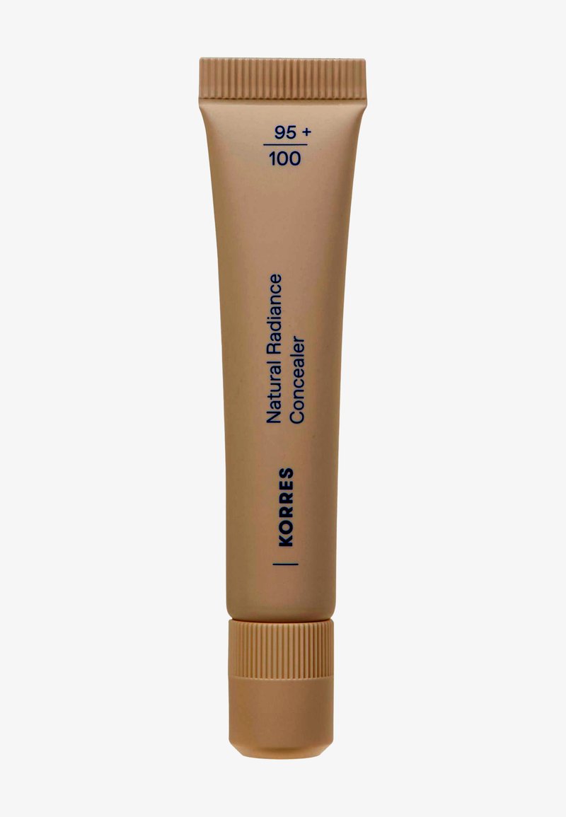 Concealer éclat naturel Korres en teinte 95+100, tube beige avec un capuchon à vis, texte vertical bleu foncé sur fond marron clair.