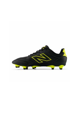 Chaussures de football noires avec des accents jaunes, présentant un design texturé, des lacets et des crampons moulés pour une adhérence sur les surfaces en herbe.