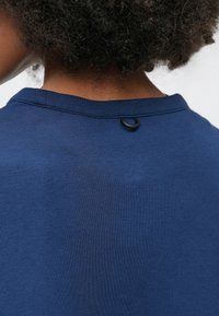 Μπλε σκούρο βαμβακερό πουκάμισο με στρογγυλή λαιμόκοψη και μικρή μαύρη θηλιά στο πίσω μέρος του γιακά. Απαλή υφή και απλός σχεδιασμός.