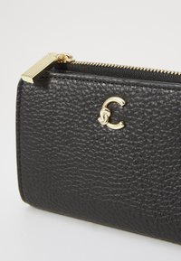 Portafoglio in pelle nera texturizzata con chiusura a zip dorata e accentuazione del logo in oro. Presenta un design resistente e una fodera liscia.