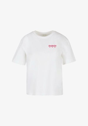 Valge lühikeste varrukatega puuvillane T-särk, mille vasakul rinnal on kolm punast südame kujundust. Mugav lõige ja ümmargune kaelus.