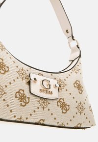 Textured beige handbag with gold floral pattern, featuring a silver hardware logo, a white strap, and a curved silhouette.