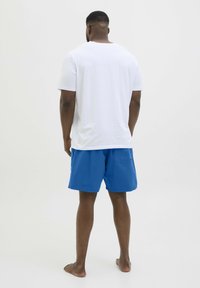 Witte short-sleeve t-shirt met een ontspannen pasvorm, gecombineerd met blauwe zwemshorts met een achterzak. Soepele textuur, casual ontwerp.