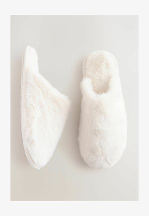 Baltos pūkuotos šlepetės su minkštu, pūkuotu paviršiumi ir apvalia pirštų dalimi. Su slip-on stiliumi, su paminkštintu vidumi ir plokščiu padu.