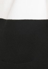 Black and white sweater featuring a soft, textured fabric. The upper section is white, while the lower section is solid black with a ribbed hem.