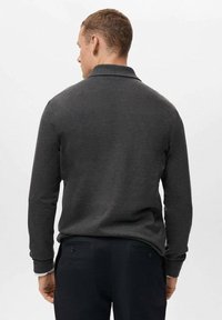 Camisa polo gris de manga larga con cuello, puños acanalados y una textura suave, combinada con pantalones negros con bolsillos traseros abotonados.