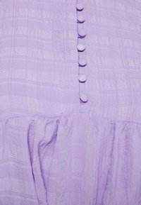 Lavendelfarbenes Kleid mit einem strukturierten, karierten Muster, das sechs passende, mit Stoff überzogene Knöpfe auf dem Rücken und einen gerafften Rock hat.