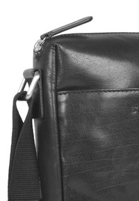 Borsa a tracolla nera in pelle con una texture liscia, forma rettangolare, chiusura a zip e tracolla regolabile in tessuto con hardware in metallo.