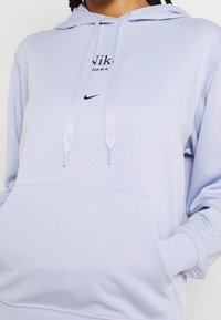 Ljuslila hoodie i mjuk tyg, med en känguruficka, snören och framtryck med "Nike" och sloganen "Just do it."
