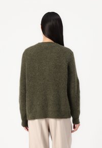 Olivkowy sweter o miękkiej fakturze, w luźnym kroju, z okrągłym dekoltem i długimi rękawami, widoczny z tyłu.