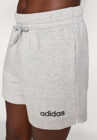 Szürke pamut rövidnadrág fekete "adidas" logóval, elasztikus derékkal és oldalsó zsebekkel, sima textúrával és térd feletti hosszal.