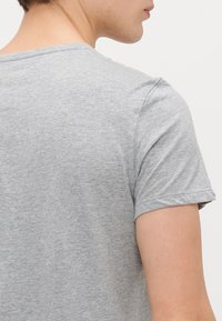 Γκ�ρι κοντομάνικη μπλούζα φτιαγμένη από μαλακό βαμβακερό ύφασμα, με απλό στρογγυλό λαιμό και χαλαρή εφαρμογή. Ορατή ραφή στις ραφές.