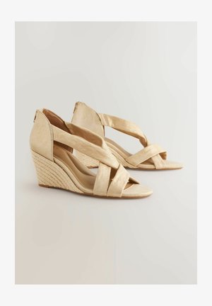 Beige Wedgesandalen mit einem kreuzförmigen Riemendesign, samtartigem Finish und mit Jute umwickeltem Absatz. Offene Zehen und hintere Fersenabdeckung.