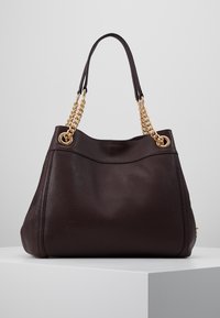 Brązowa torba na ramię ze skóry o fakturowanej powierzchni, wyposażona w złote łańcuszkowe paski i okrągłe oczka, zaprojektowana w luźnym fasonie.