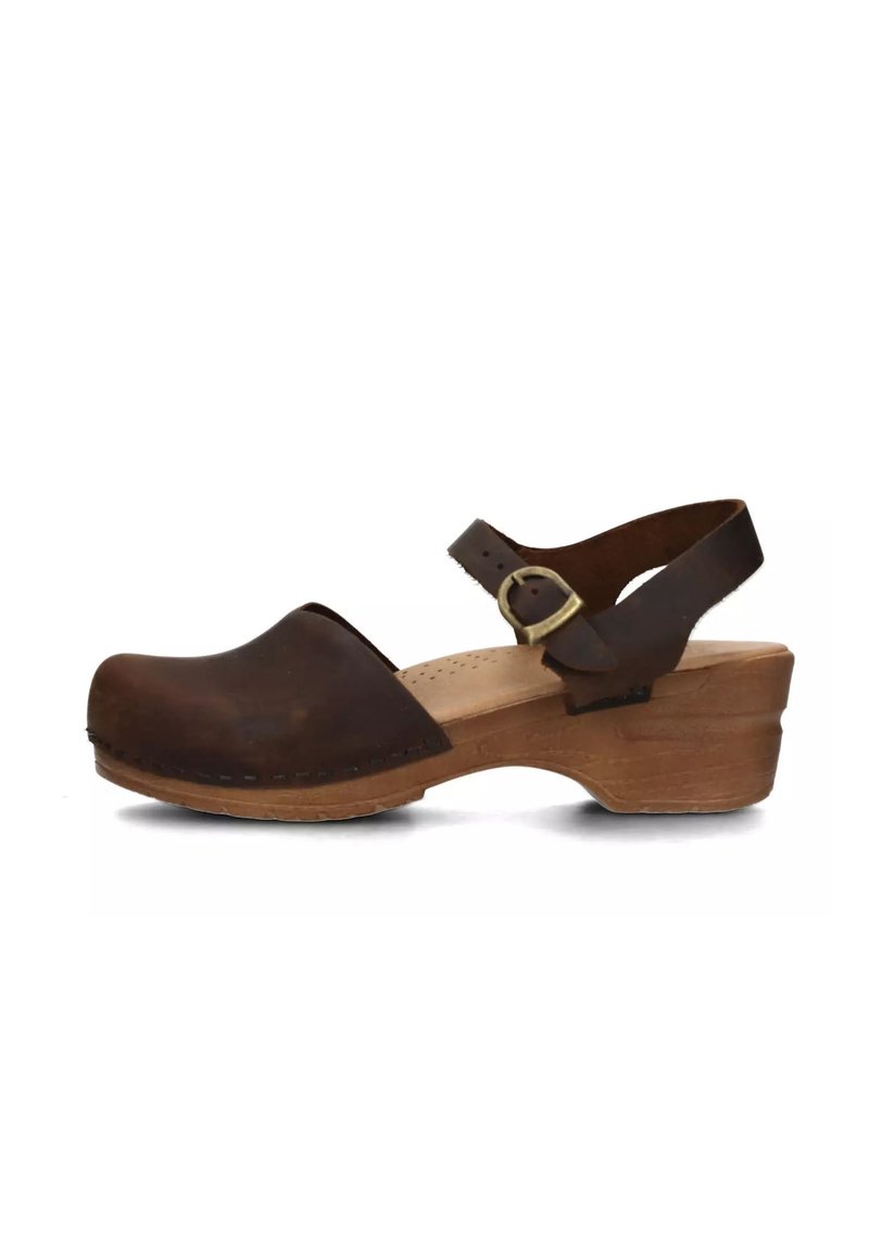 Zoccolo in pelle marrone con punta arrotondata, tacco aperto e fibbia regolabile. Suola a zeppa in legno per un'elevazione. Dettagli di cucitura minimi.
