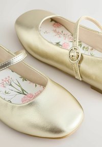 Zlaté balerínky s guľatou špičkou, kovovým remienkom a stielkou s kvetinovým vzorom, so hladkým, lesklým povrchom.